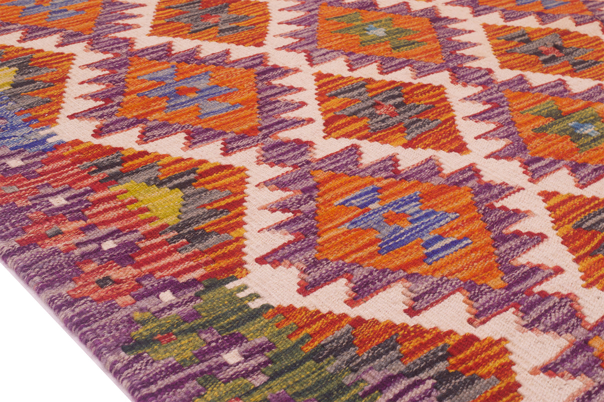 Kilim rug detail with purple border and orange pattern blocks on off-white ground.