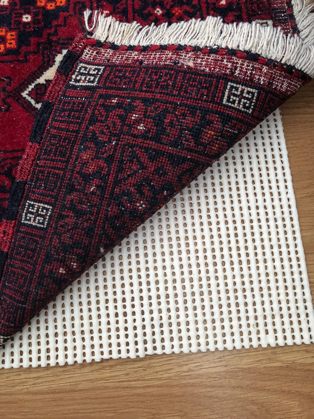 AKO Profilo V Anti-Slip Rug Underlay laid on a hard laminate floor with Red Afghan Rug on top.