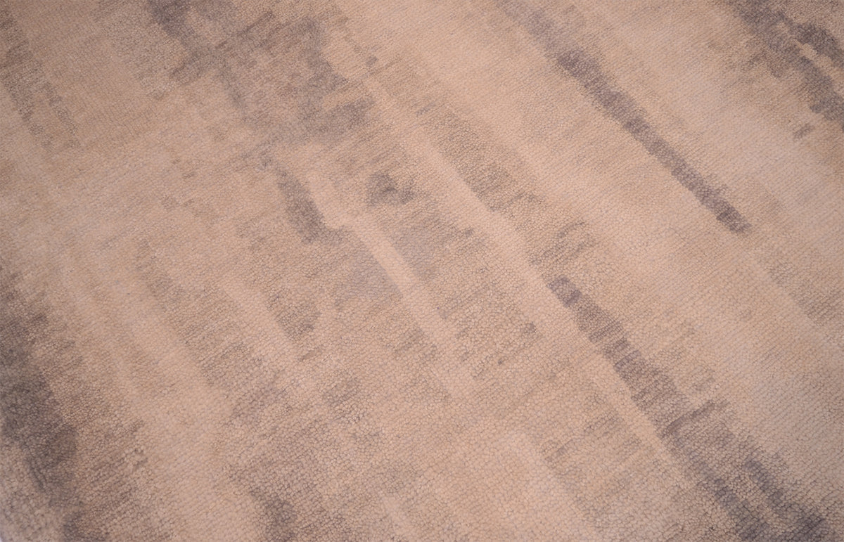 Close up detail of modren abstraxt handknotted Indian Carpet with gentle neutral tonalies of cream-beige ground and soft fluid greys.