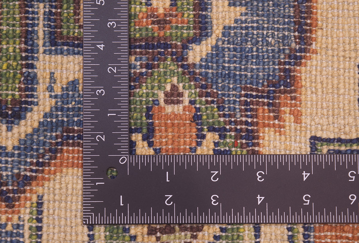 Close-up of the hand-knotted back of an Afghan Heriz design handmade rug with a dark metal ruler showing measurements in centimetres and inches to help show scale.