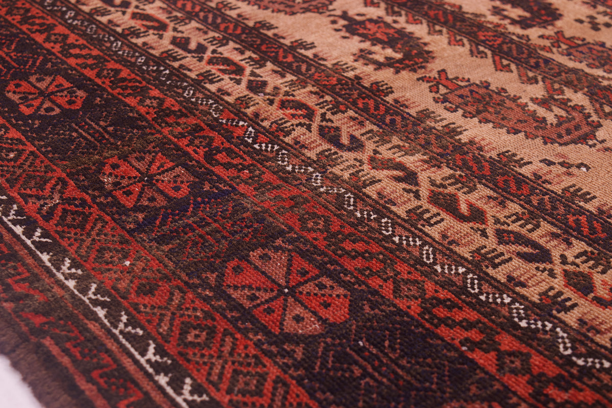 Close-up of a patterned Antique Belouch prayer rug with woven bands in rust red, dark brown, and beige, showing detailed textile texture and geometric motifs.