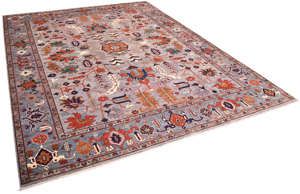 Angled view of impressive handmade carpet with Antique Persian Serapi design with modern colours with neutral grey field with bluish border with all over floral geometric design with orange, golden ochre tones, teal, blue and ligth mauve accents. Highlights of light cream in border and main field.