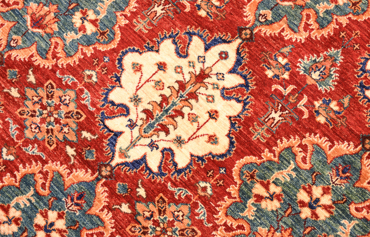 A close-up of a traditional Afghan handmade Bakhtiar carpet featuring a prominent cream central medallion surrounded by red, blue, and orange floral motifs.
