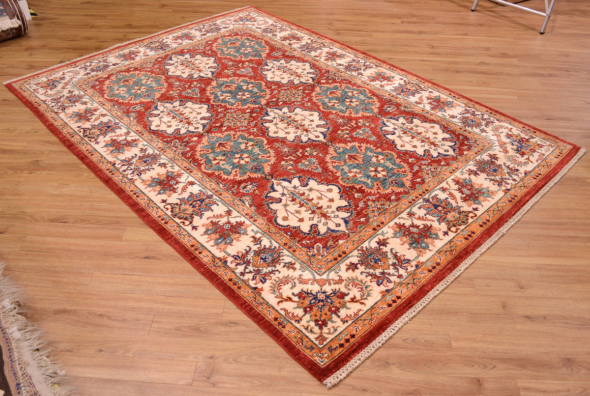 A traditional oriental Afghan Bakhtiar area rug with a red field, beige floral motifs, and blue accents, displayed on a light wood floor.