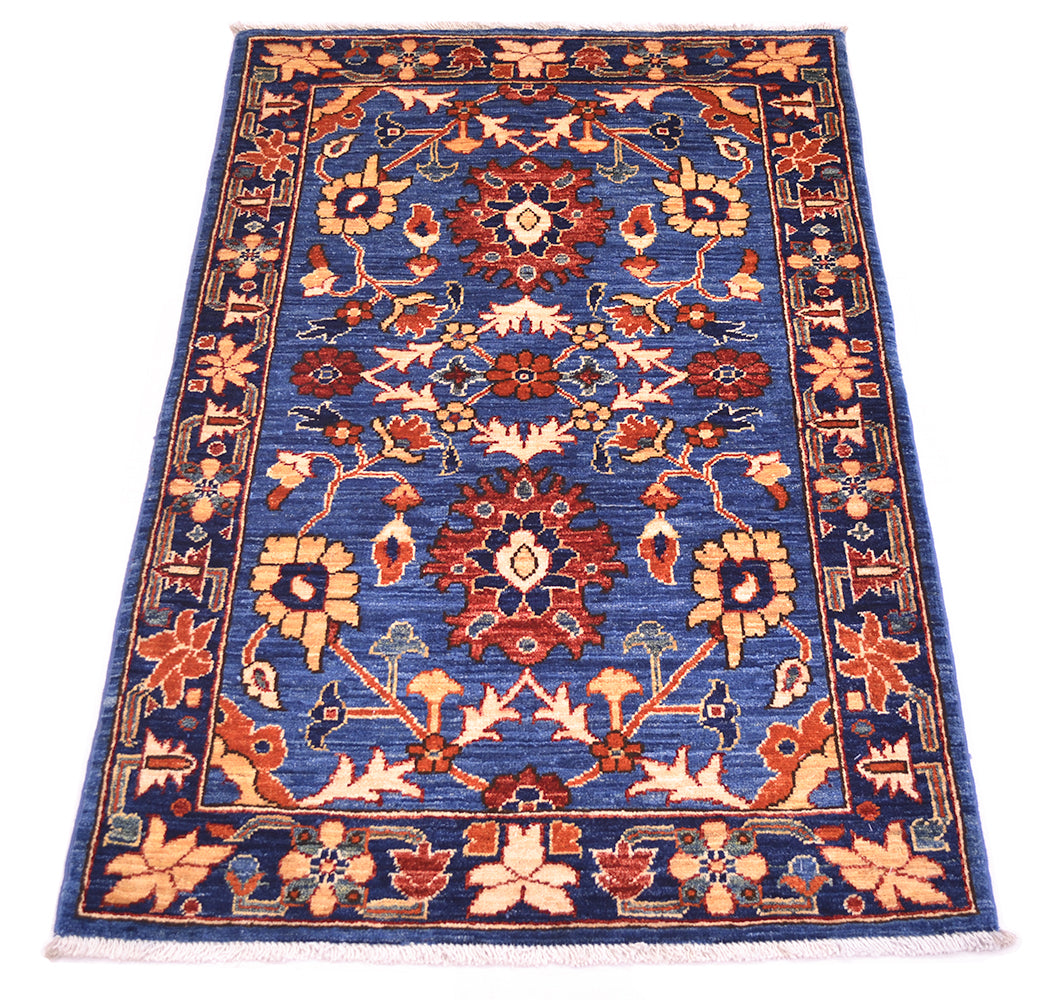 A 4x2'8 rectangular traditional Afghan Aryana blue rug with a blue field, featuring intricate floral and geometric patterns in red, beige, and orange, finished with white fringe on the top and bottom.