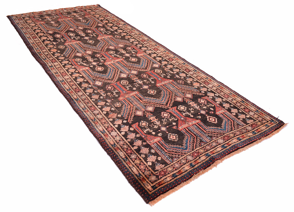 A traditional long belouch runner rug with a dark charcoal-black field, geometric tree medallion motifs, and a patterned border in muted red, beige, and teal tones, shown on a plain white background.