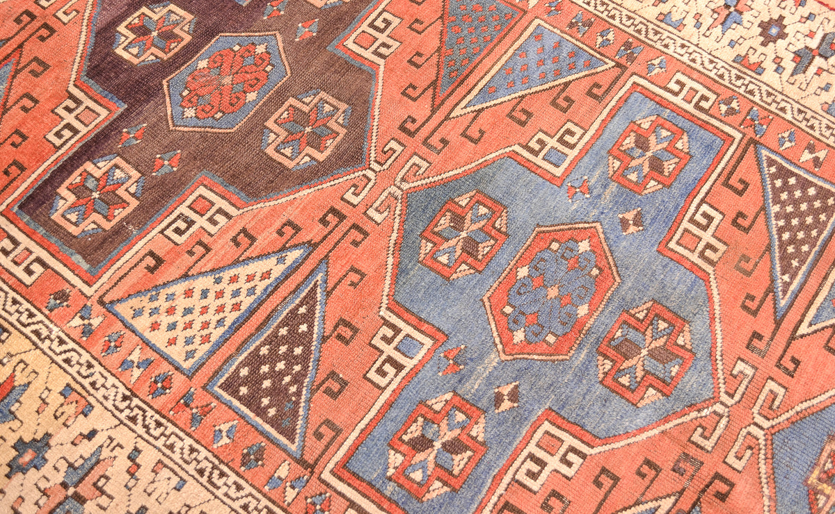 Close-up of Antique Bergama rug pattern with diamond motifs in blue, rust, and cream