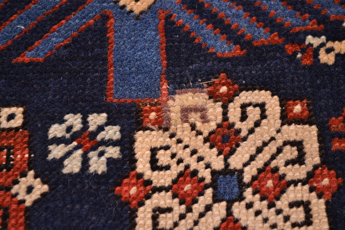 Rug texture close-up with navy field and cream medallion shapes outlined in red-orange.