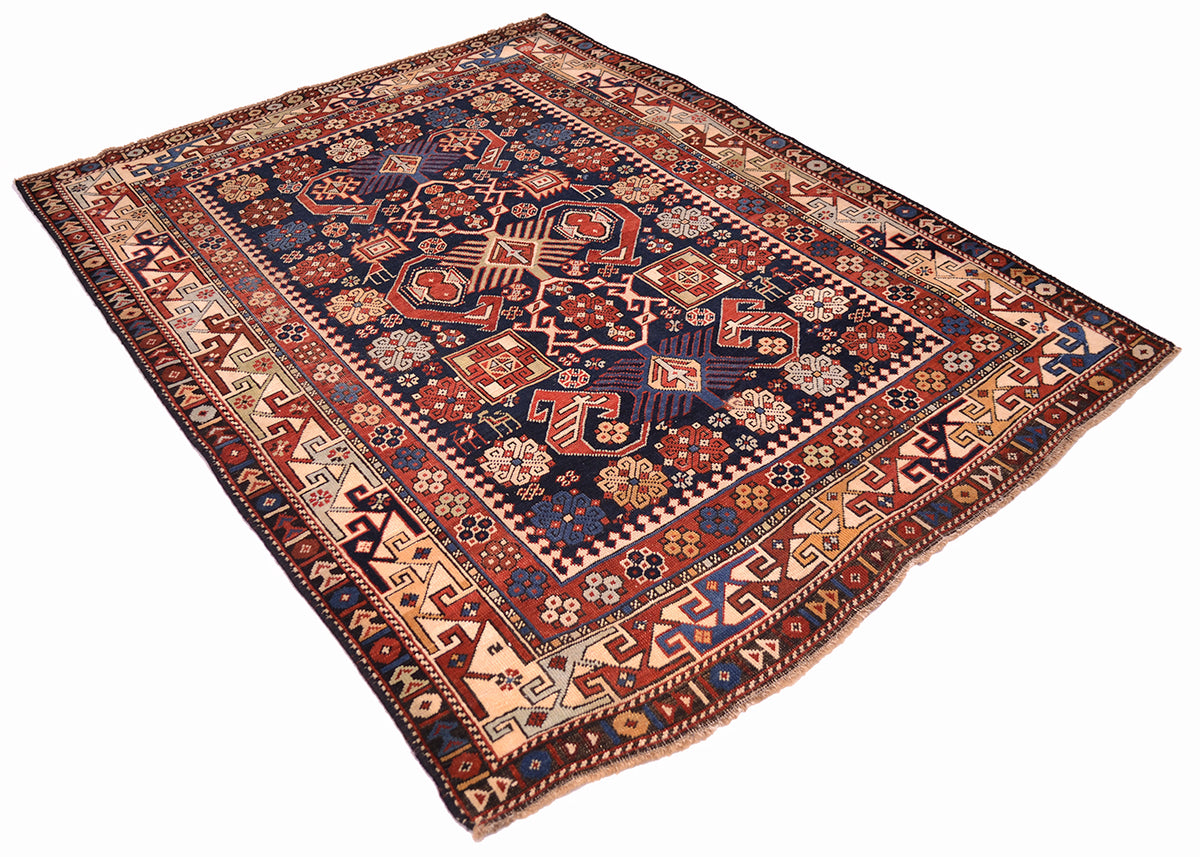 Antique rug laid diagonally; navy blue, red, and cream geometric border with central motifs.