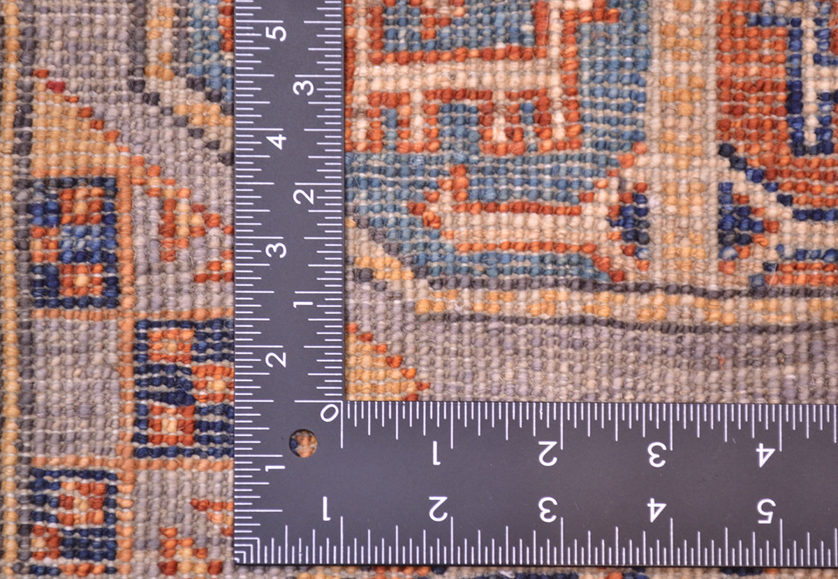 Close-up of the hand-knotted weave of a Afghan Fil Pai patterned small rug with a metal L-shaped ruler showing measurements in inches to indicate scale of the knotting.