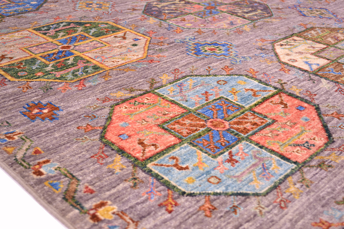 A close-up of a traditional Afghan Fil Pai patterned rug with a muted grey base and large geometric medallions in coral, light blue, green, and brown.
