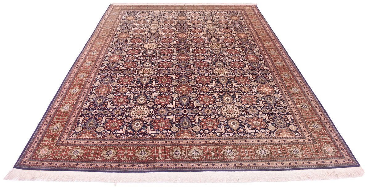 A rectangular oriental Hereke rug with an intricate floral and geometric pattern in shades of navy blue, rust red, beige, and brown, shown flat against a white background.