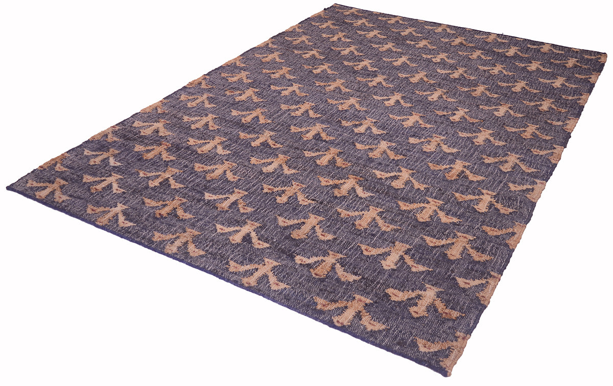 A rectangular area rug with a dark slate blue-gray base and a repeating tan abstract pattern, shown at an angle on a white background.