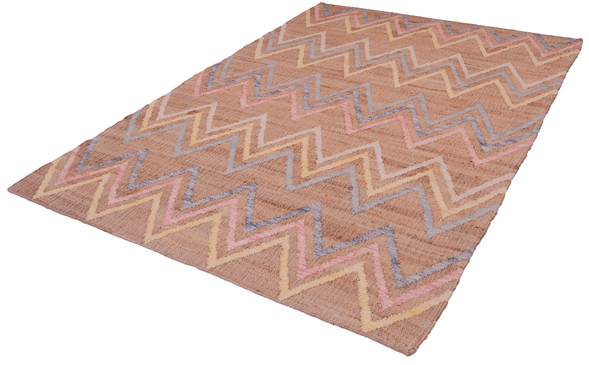 A rectangular woven area rug with a zigzag chevron pattern in shades of brown, beige, pink, and blue, shown at an angle on a white background.
