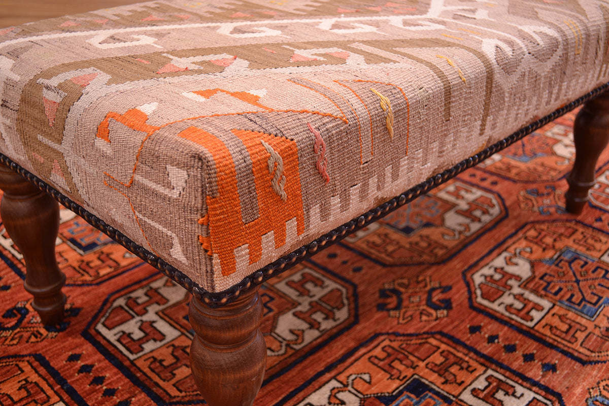 Close up design of kilim bench with vintage kilim with beaded edging and soft pastels colours with hints of oragen and coral pinks as well as beige and light olive greens.