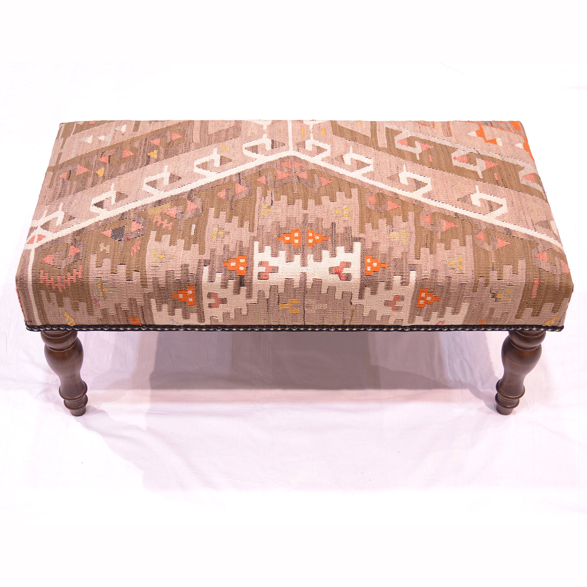 Anatolian Kilim Bench Stool with geometric design with vintate kilim in colours of muted grey, olive & cream with flashes of orange and coral pink. on a white background.