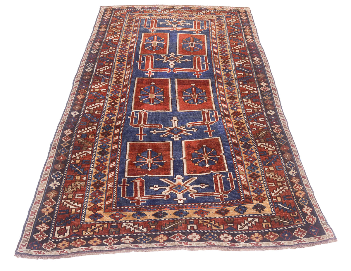 A traditional hand-knotted geometric antique Caucasian Karagashli rug with a dark blue field, red-orange central panels, and beige borders, shown flat against a white background.