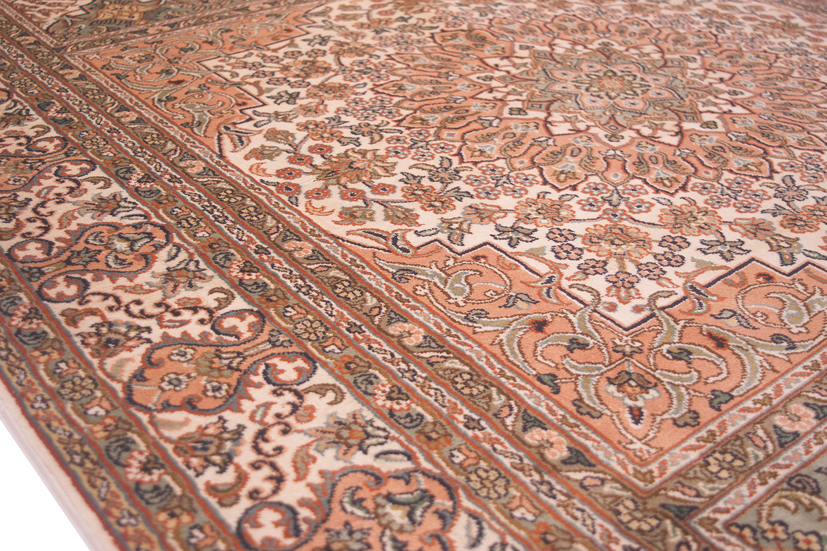 A close-up view of an ornate traditional silk Kashmir rug with a complex floral pattern in terracotta, beige, brown, and muted blue tones.