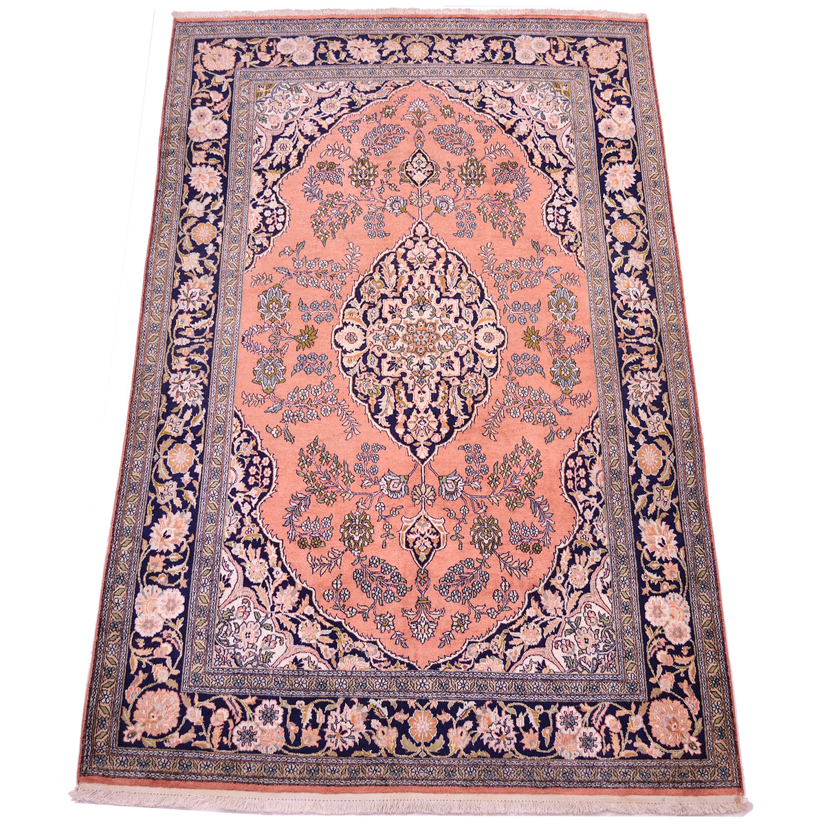 A traditional Kashmir Silk area rug with a dusty pink central field, a navy blue border, and intricate floral motifs in beige, green, and blue.