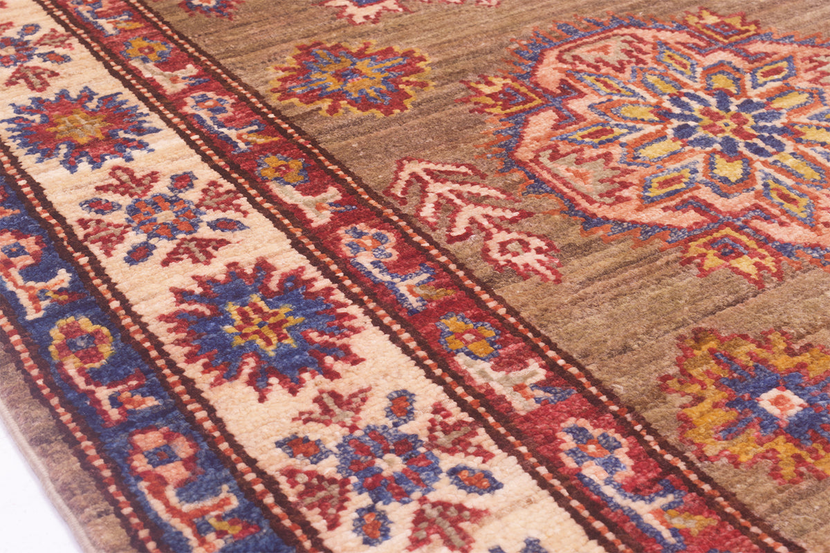 A close-up of a traditional patterned Afghan runner rug with a brown field, cream border, and red, blue, and yellow floral medallions.