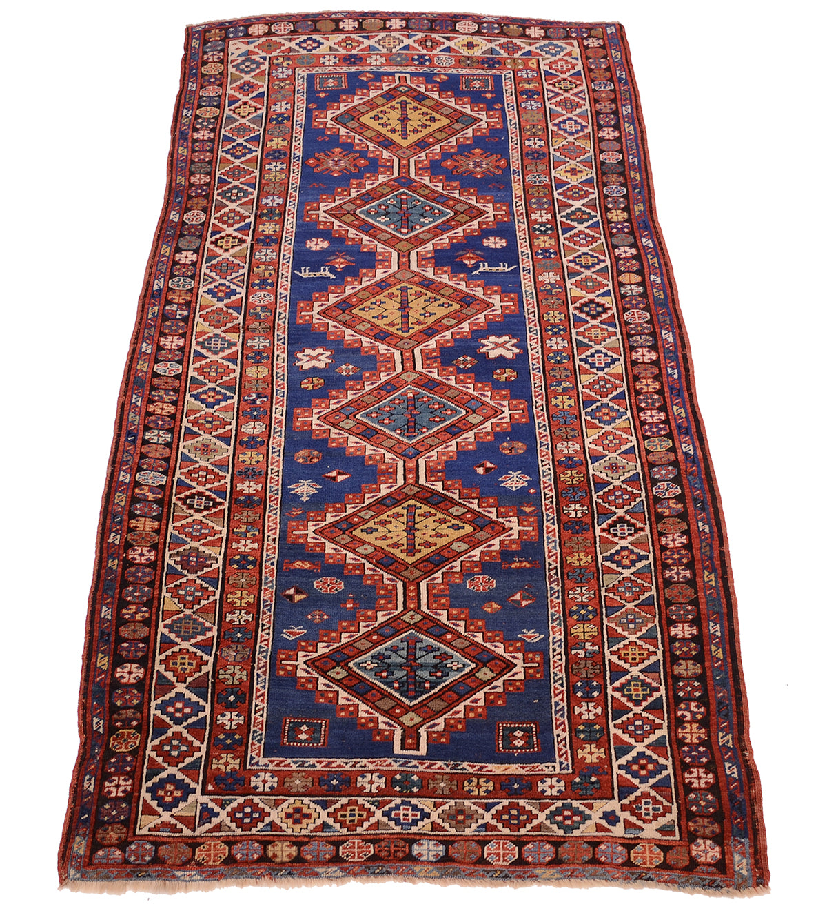 Overall views of antique kazak ling rug with mulitoclours an ruch blue fields with six interconnecting stepped medallions and multiple geometric borders. Colours of red, blue, golden yellow, teal and black.