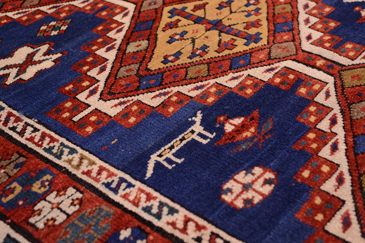 Close up detail of main field of handknotted antique multicoloured rug with improvised motifs of stylized roundels as well as little creatures/ sheep dogs flanked the central connecting medallions.