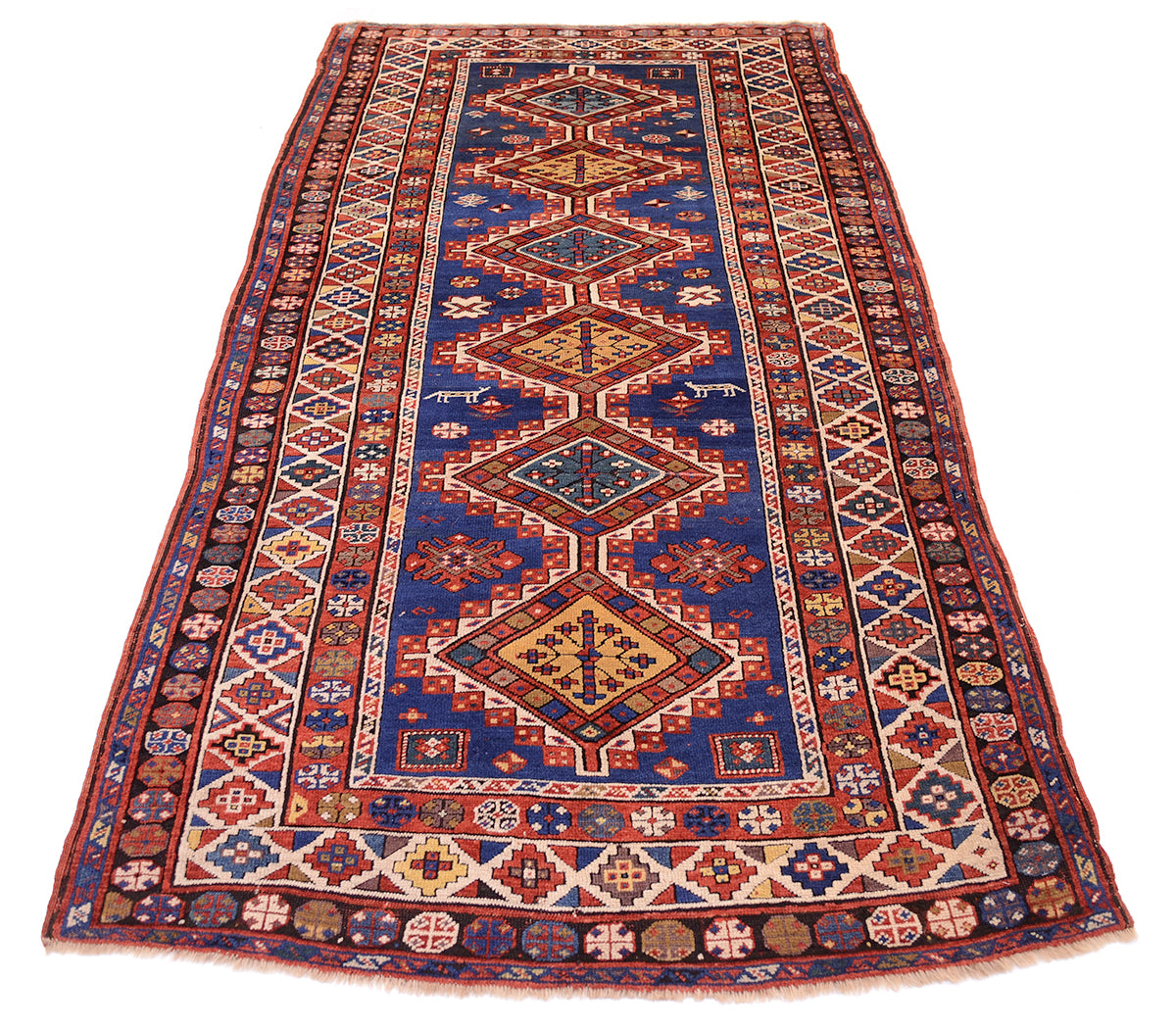 Overall views of Antique kazak carpet with blue firlds and six connecting medallions centre with multicoloured palette and multiple geometric borders. Stunning array of primary and secondary colours.