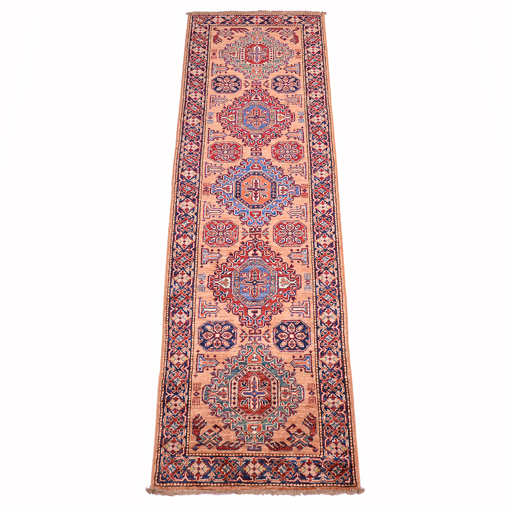 A traditional handmade fine Kazak runner rug with a peach-pink field, featuring red and blue medallions and floral motifs, bordered by red and navy blue patterns, shown flat against a white background.