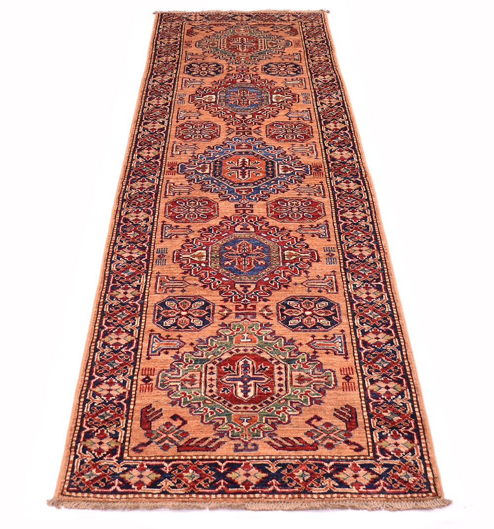 A long rectangular Afghan Kazak runner rug with intricate geometric and floral motifs in peach, navy, red, beige, and green, shown flat against a white background.