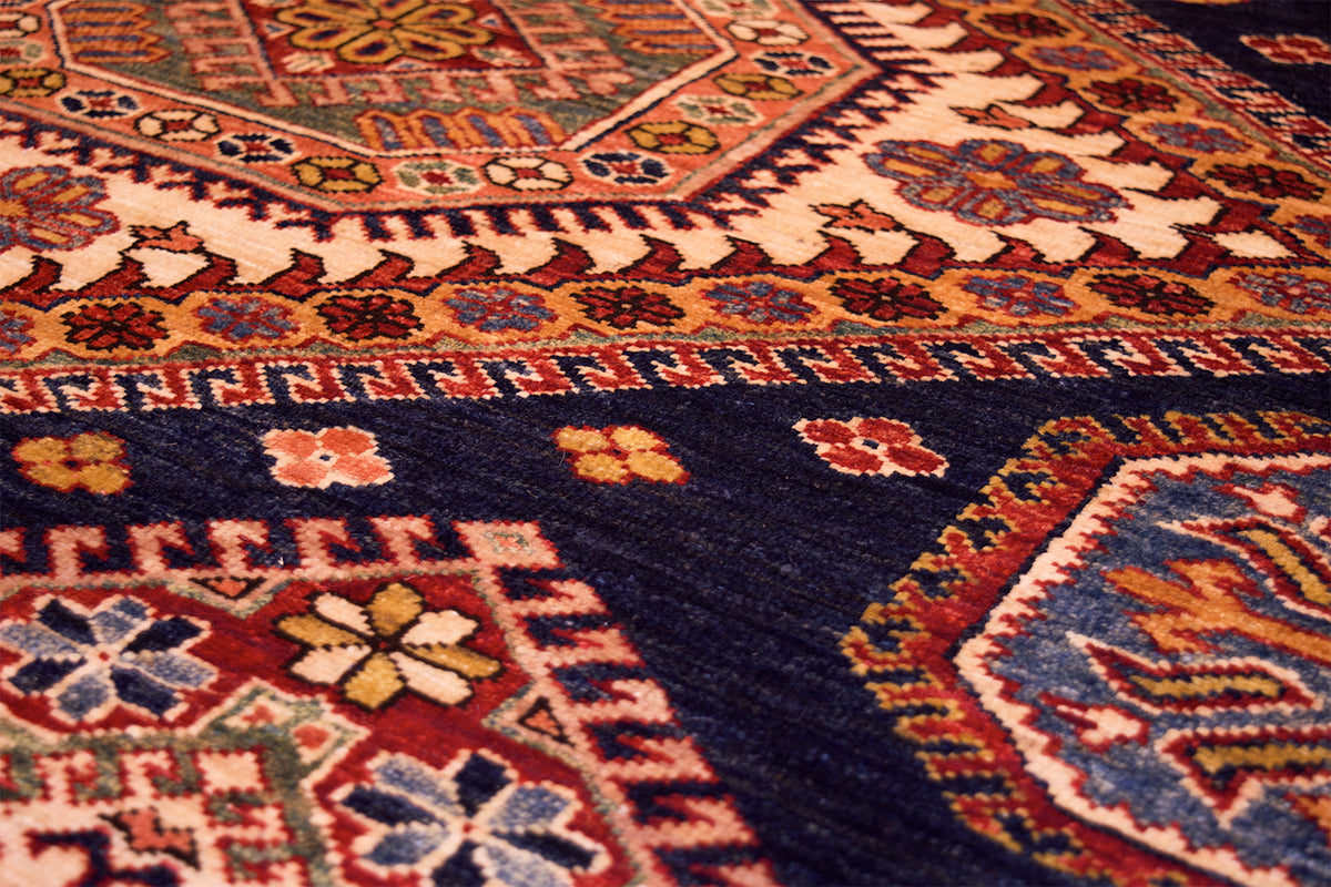 Corner close-up of navy kazak rug with repeating floral and lattice motifs