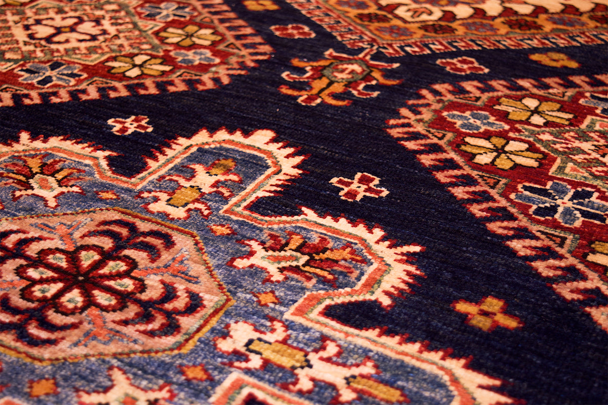 Close-up of navy kazak rug field with orange and cream diamond medallions