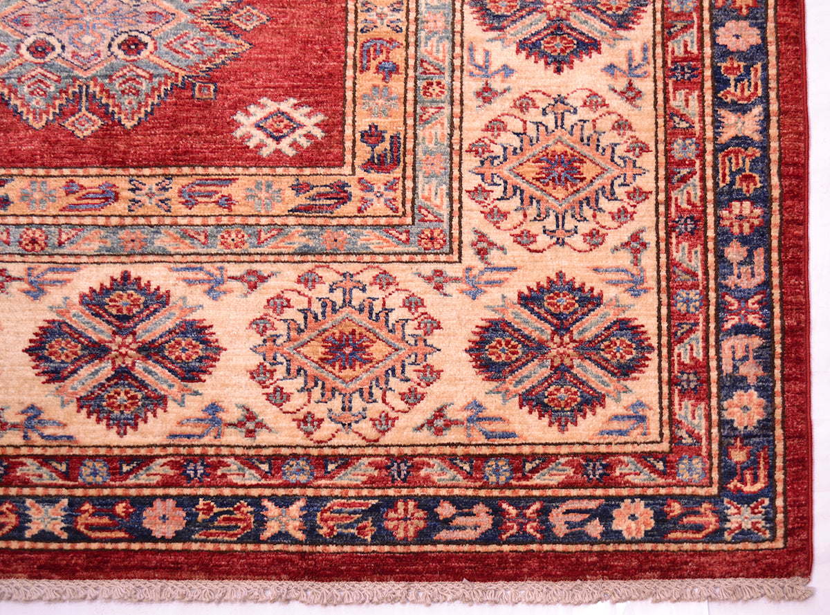 A close-up of a Large handmade red fine Kazak carpet showing a corner detail. The rug features a deep red field, a cream-colored inner border, and a dark navy blue outer border with intricate geometric and floral motifs in red, blue, and beige.