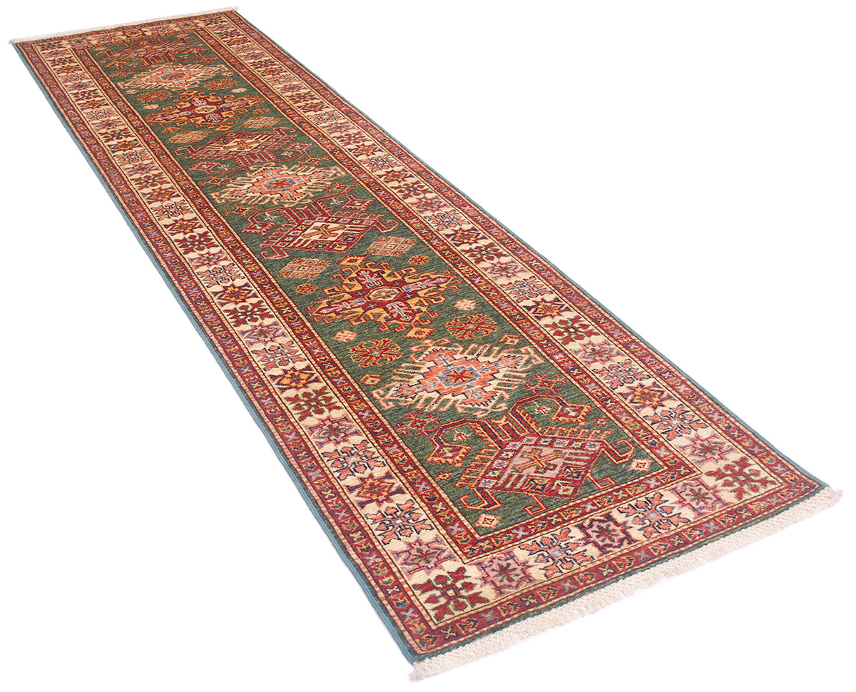 A long Fine handmade green Afghan Kazak Runner with an intricate traditional pattern, featuring a green center field, red and beige borders, and cream fringe, shown on a plain white background.