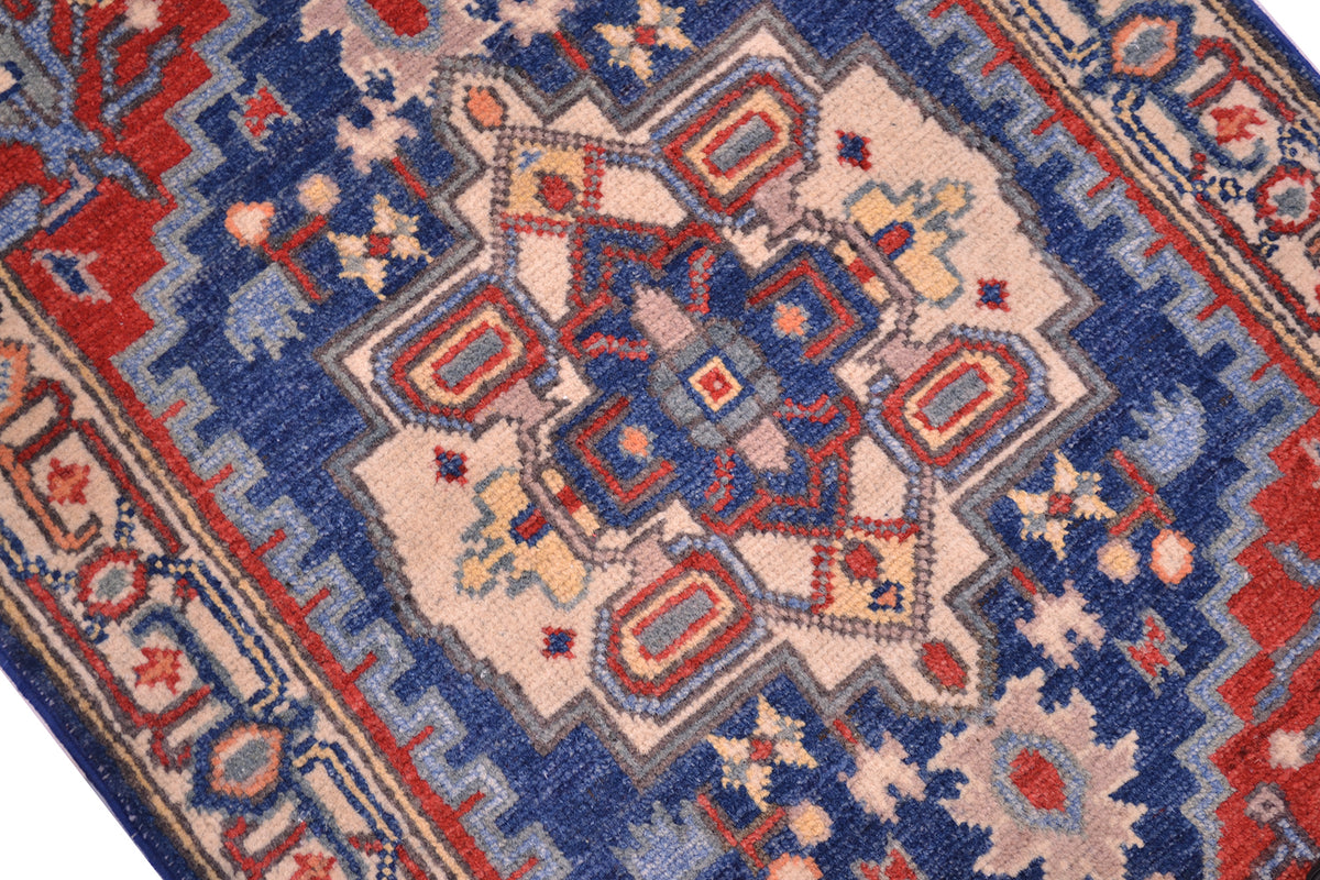 Close-up of Heriz Kazak rug with blue, red, and cream diamond motifs and border details.