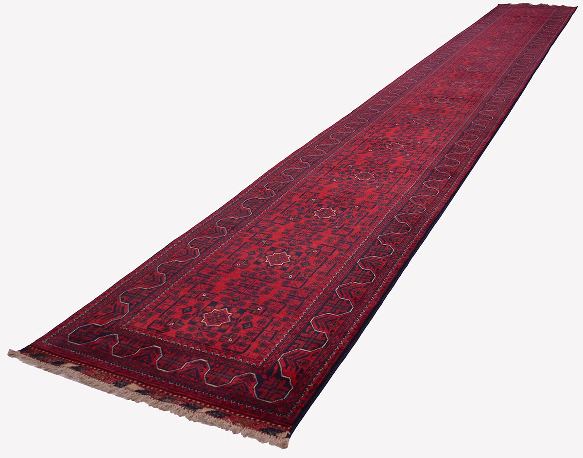 A long red oriental runner rug with dark blue and beige patterns, shown diagonally on a plain white background.