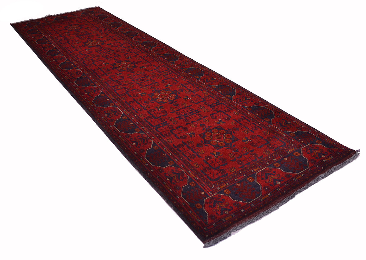 A long rectangular red afghan runner rug with dark navy blue borders and intricate floral motifs, shown on a plain white background.