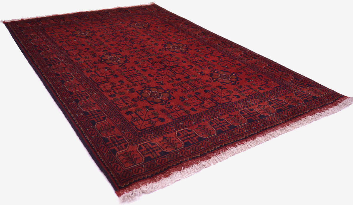 A traditional Afghan area rug with a deep red field, dark navy blue borders, and light fringe, shown from an elevated angle on a white background.