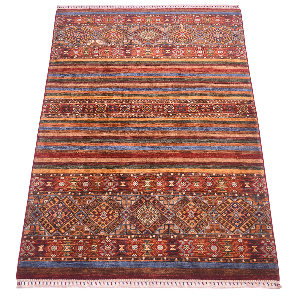 A rectangular hand-woven Khurjeen area rug with a traditional tribal design, featuring horizontal bands of red, blue, brown, and gold geometric patterns, finished with a fringed edge.
