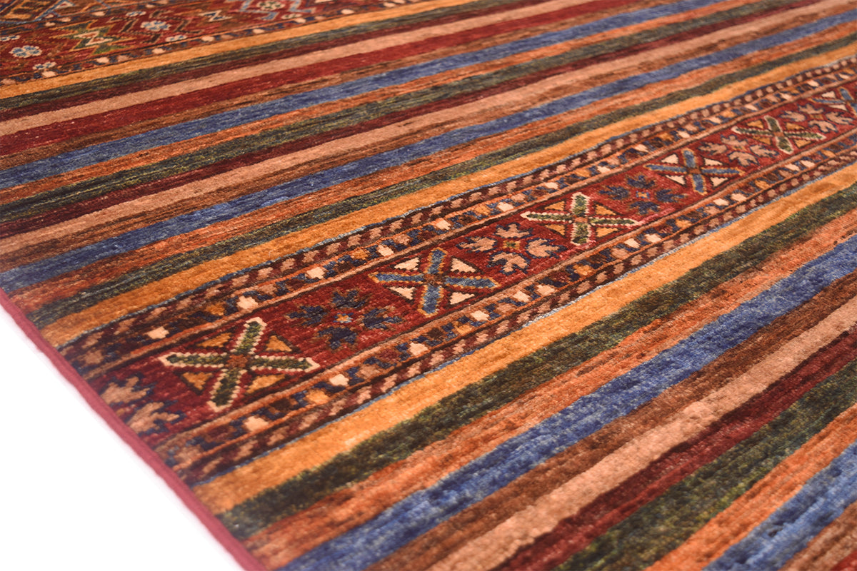 A close-up of a patterned Afghan Khorjin design area rug with horizontal stripes in rust orange, blue, olive green, and red, featuring a central geometric border.