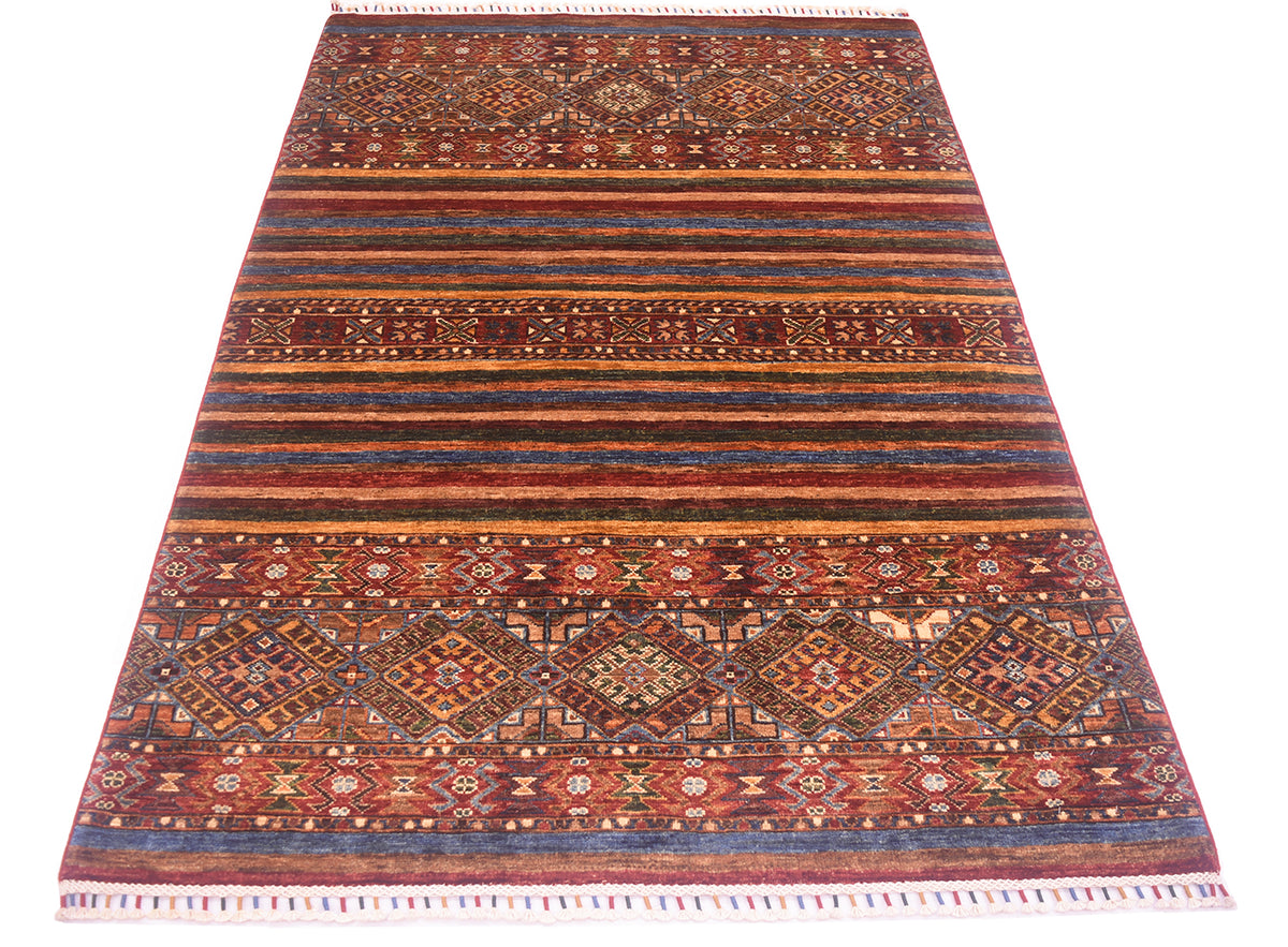 A rectangular Afghan Khorjin design rug with a traditional tribal design, featuring horizontal bands of geometric patterns in red, blue, brown, and beige, finished with white fringes on the top and bottom.