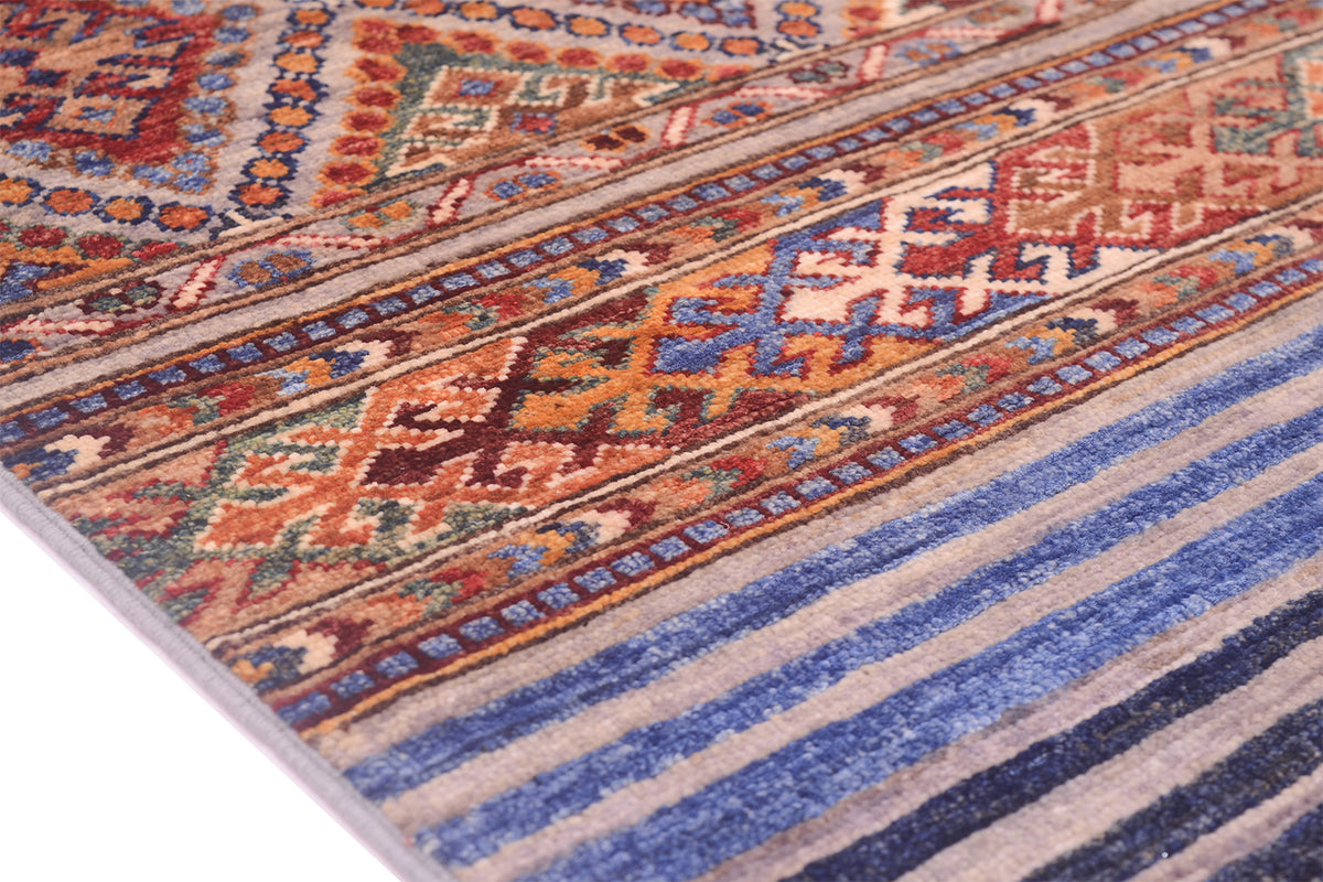 A close-up of a patterned Afghan Khorjin Runner rug with geometric and striped motifs in blue, beige, rust, brown, and cream.