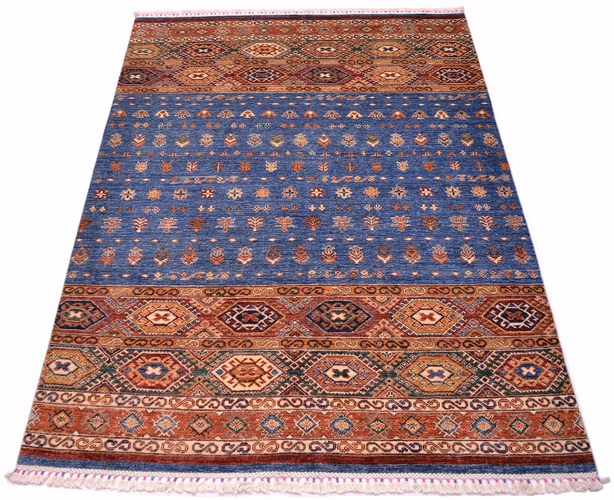 A rectangular Afghan Khorjin area rug with a traditional geometric pattern, featuring a dominant blue field with orange, red, and beige borders and motifs, finished with white fringe on the top and bottom.