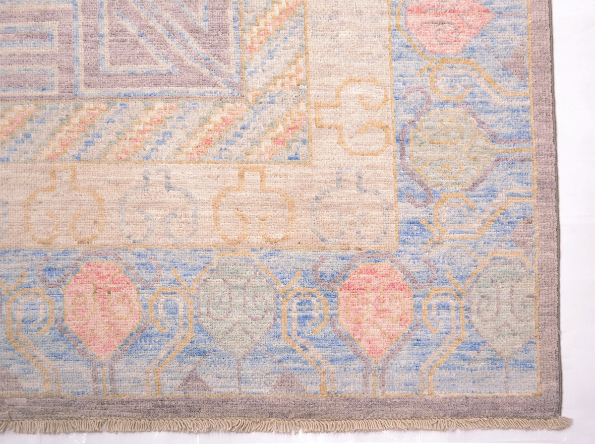 Corner detail of Afghan Khotan carpet with blue, green and light pink semi-geometric border with cotton warp fringes.
