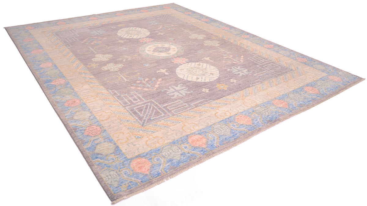 Angled view of Handknotted Afghan Khotan design carpet with soft colours of gold, cream, powder blue, coral pink and cream with a soft grey main field colour. Shown on a white background.