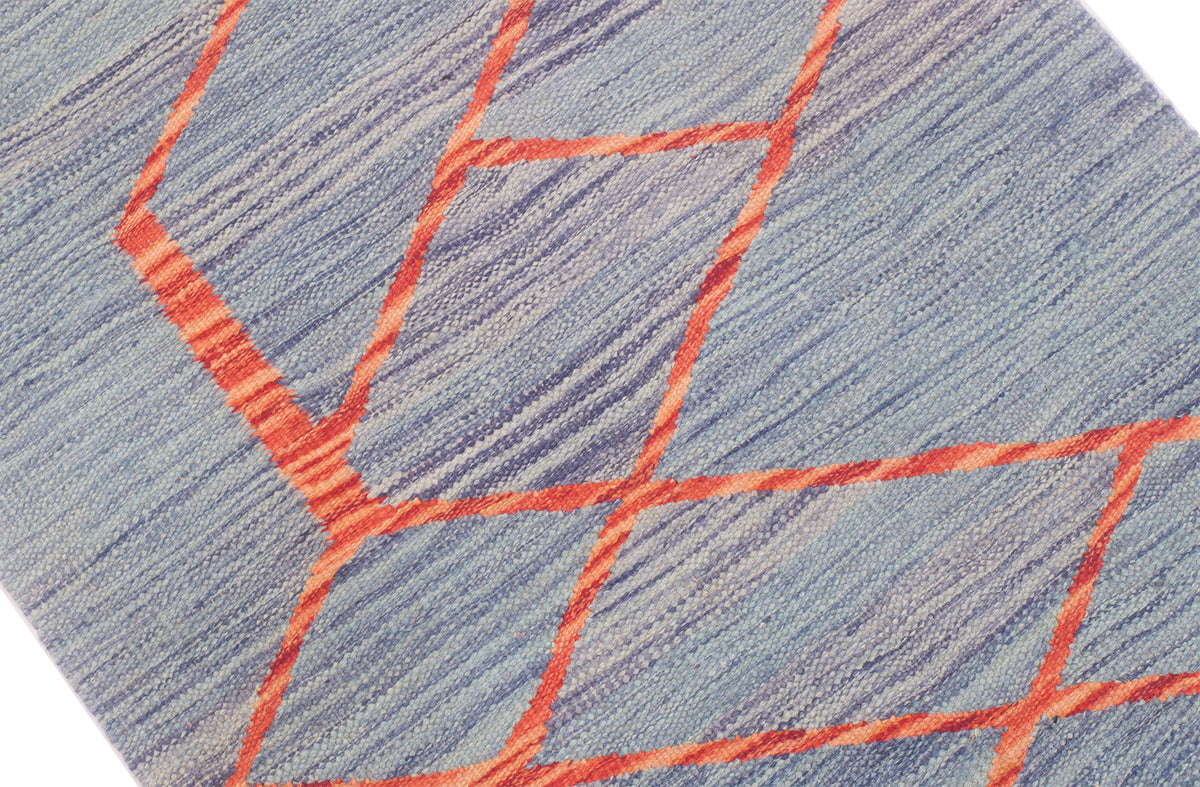 Close-up of a handwoven modern design Kilim runner with a blue-grey base and bright orange geometric kintsugi pattern.