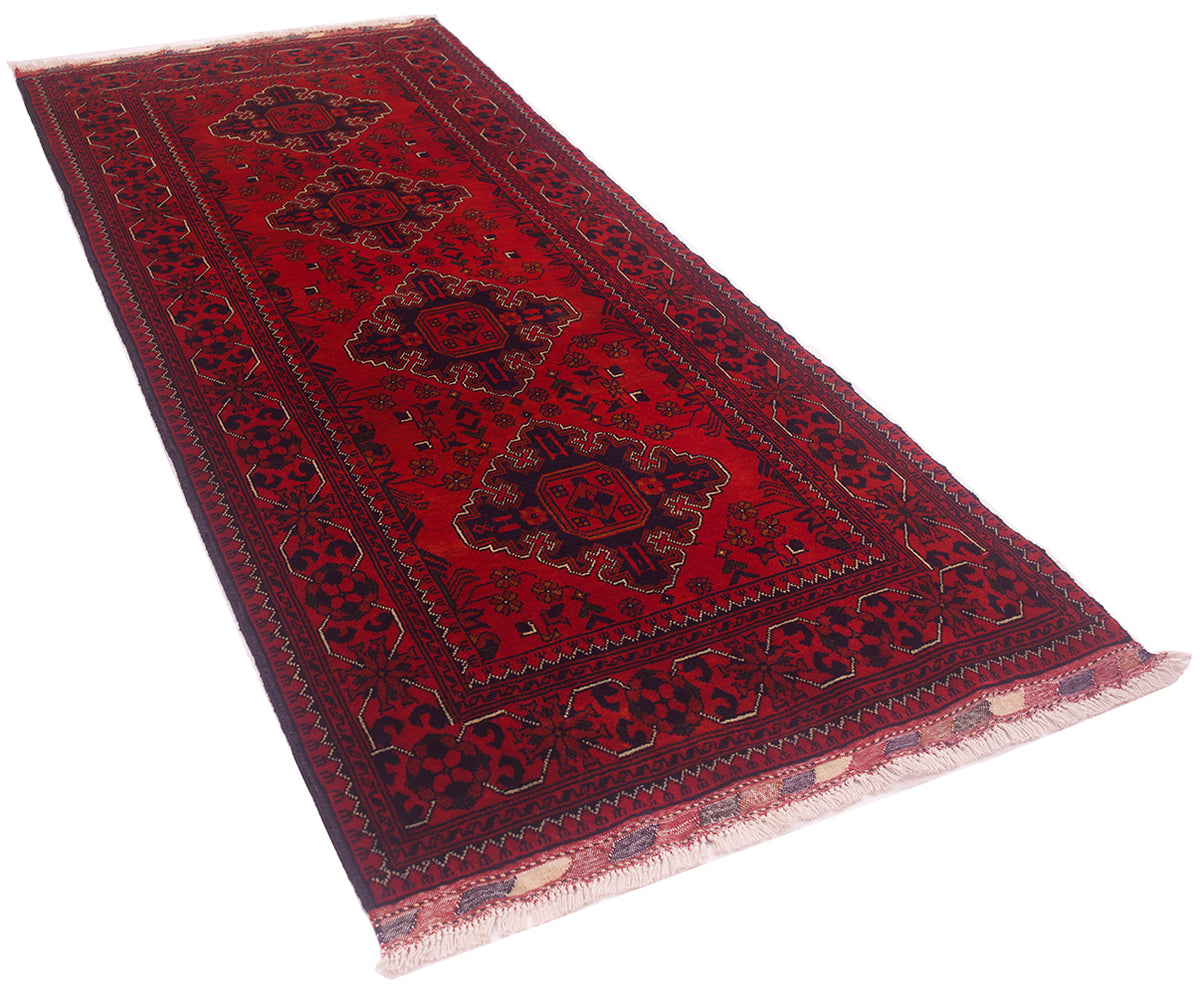 A traditional afghan runner rug with a deep red field, dark navy blue borders, and four central medallions, finished with a light fringe.