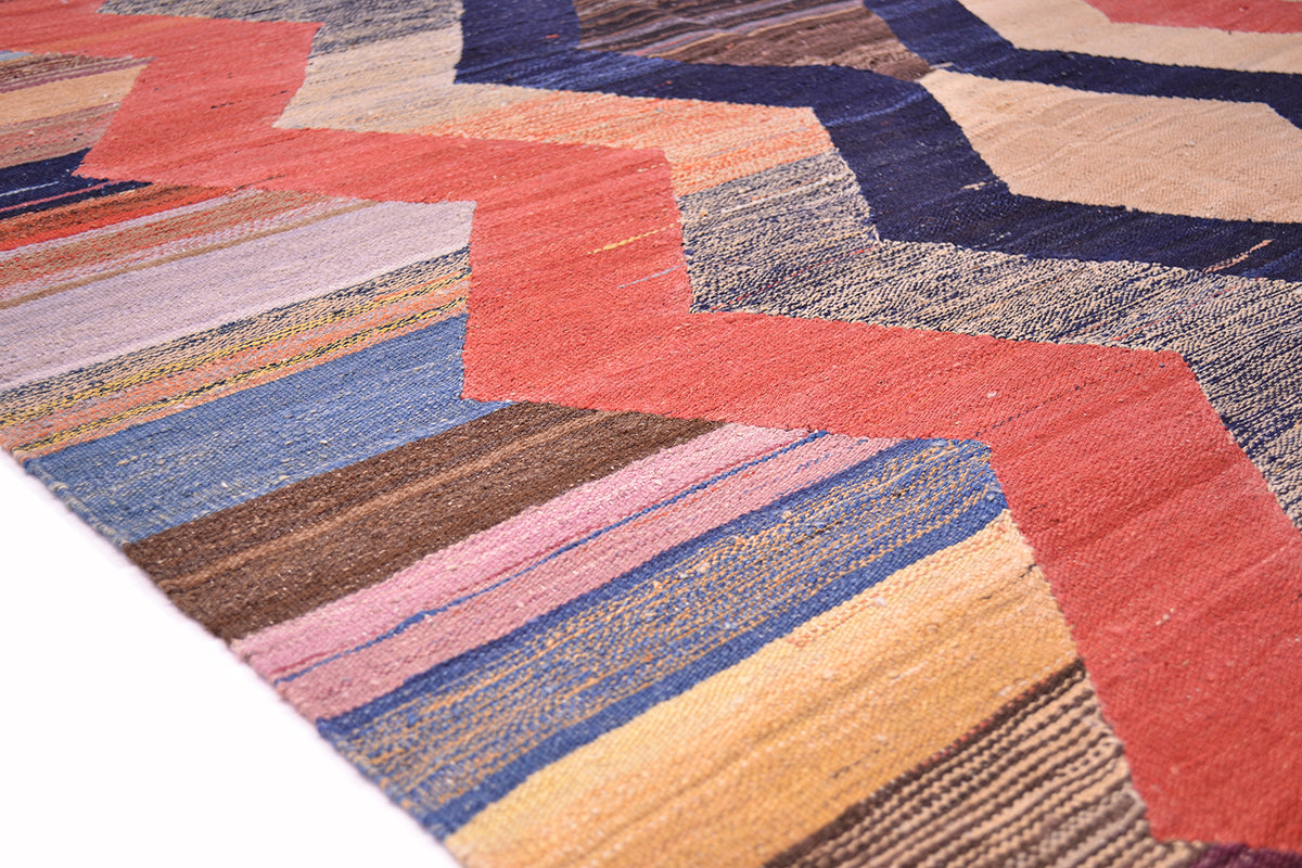 Kilim rug corner detail with red chevron and multicolor striped bands