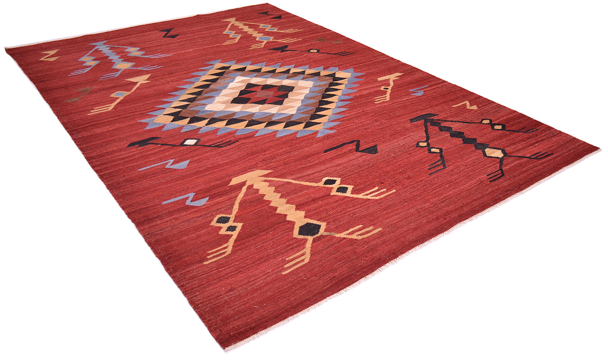 A rectangular red kilim area rug with a Southwestern geometric pattern, featuring tan, black, and light blue details, shown on a plain white background.