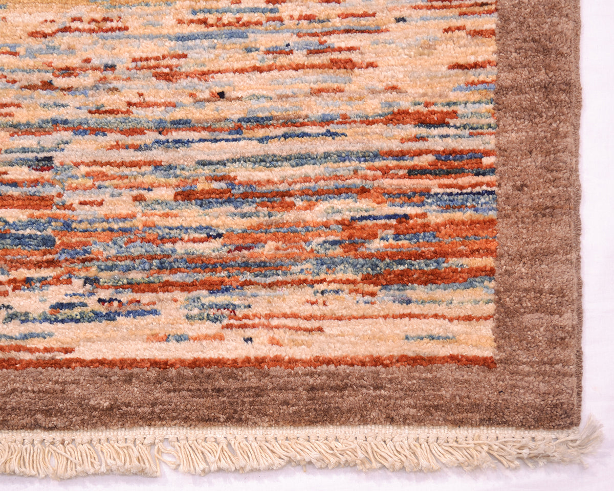 Close-up of a handmade Afghan Gabbeh rug corner showing a cream and tan field with horizontal rust orange and muted blue stripes, plus a medium brown border and cream fringe.