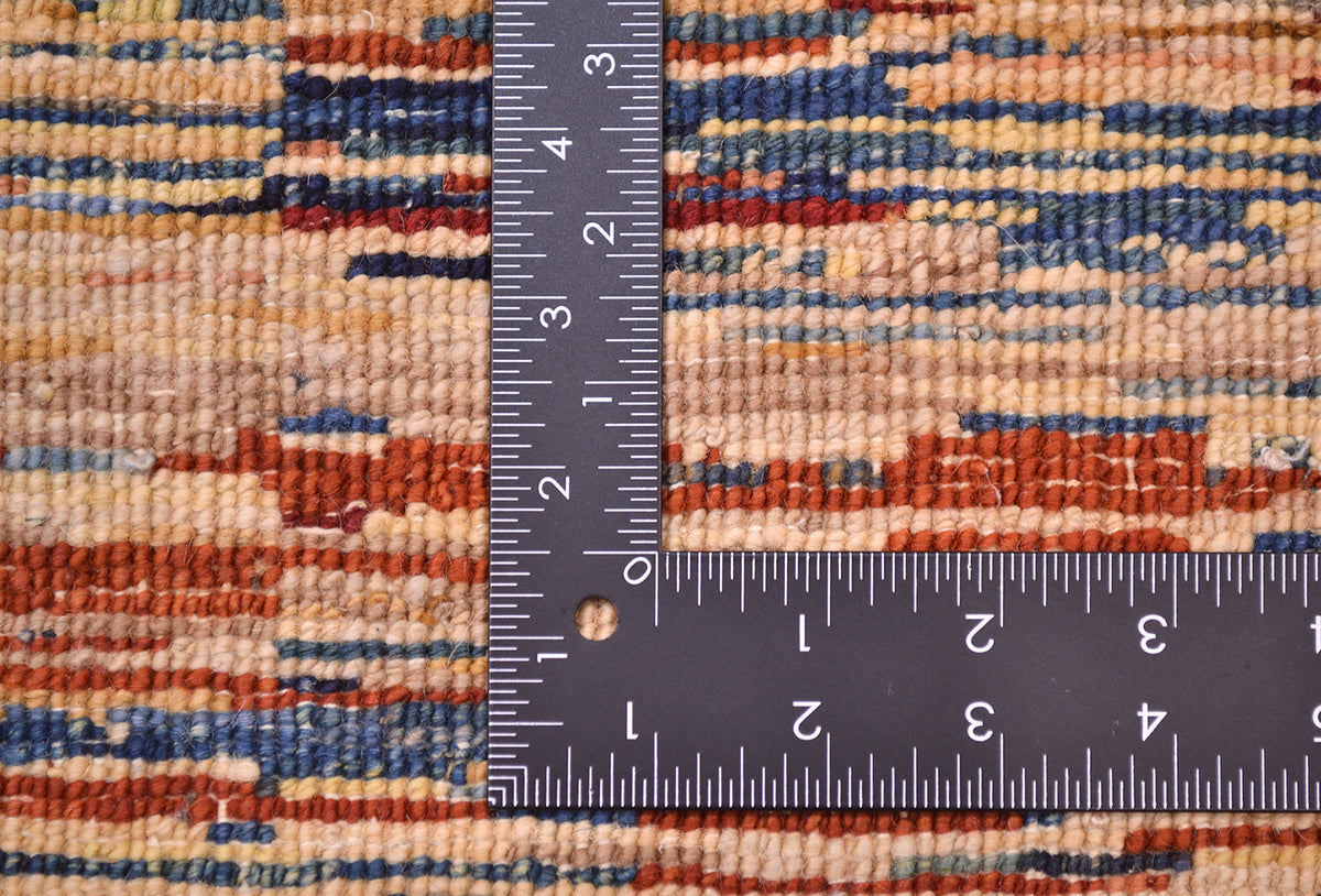 Close-up of the hand-knotted back of an Afghan Gabbeh rug with horizontal stripes in beige, blue, rust orange, and brown, shown with a black metal ruler to show scale of the knotting.